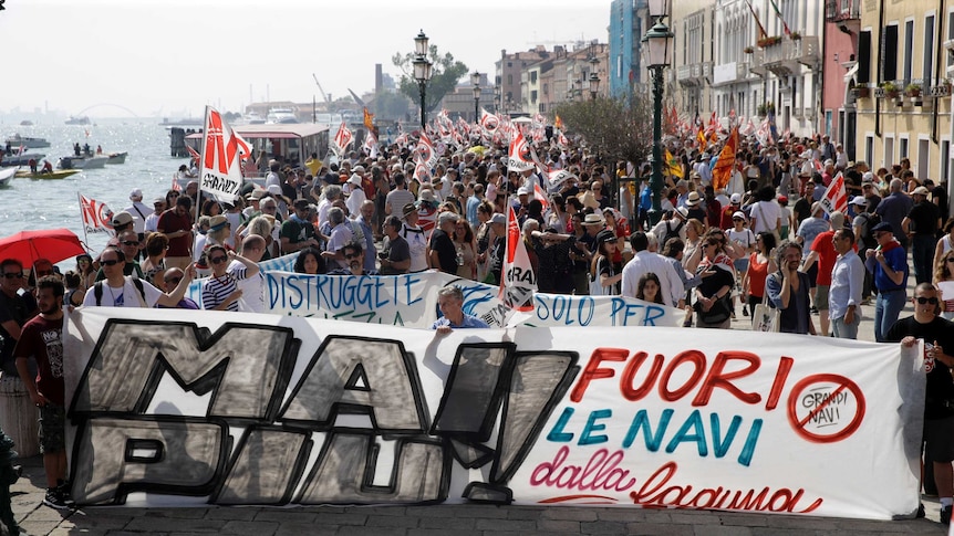 Hundreds of protestors stand alongside the lagoon in Venice, Italy amid a protest.