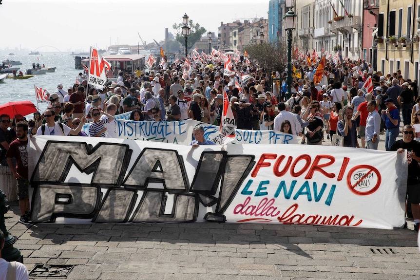Hundreds of protestors stand alongside the lagoon in Venice, Italy amid a protest.