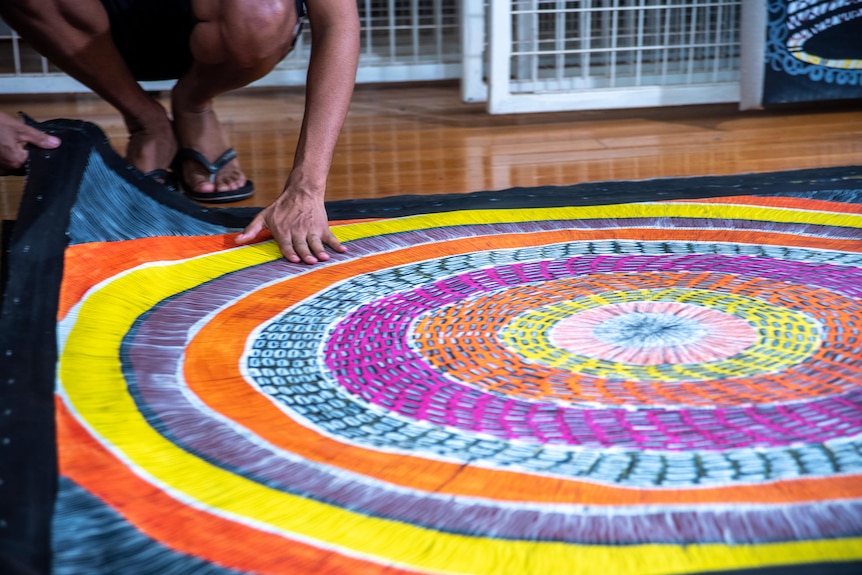 A hand is near a colourful artwork that depicts circles of colours. 