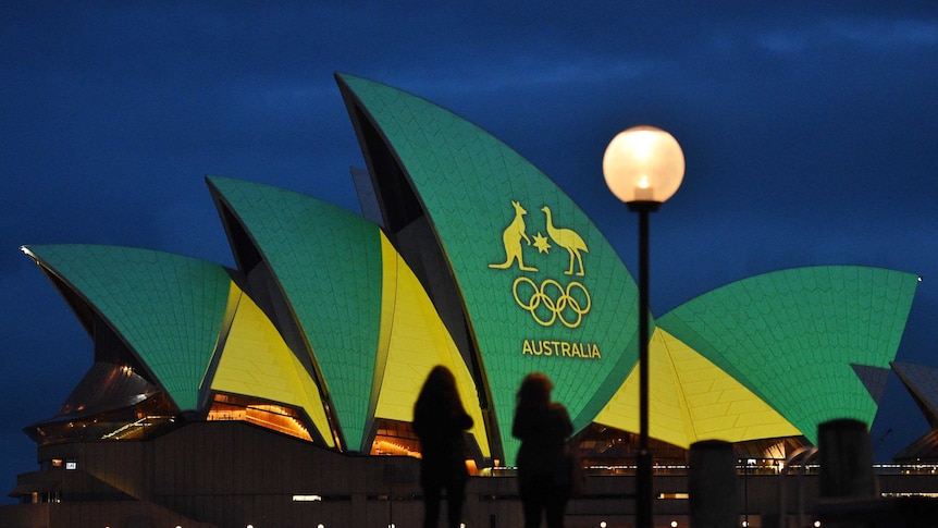 The Sydney Opera House is illuminated with the green and gold