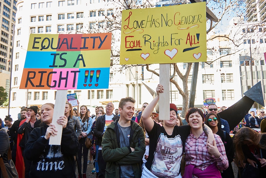 Protesters hold signs saying "equality is a right" and "love has no gender" during marriage equality march in Sydney.