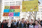 Protesters hold signs saying "equality is a right" and "love has no gender" during marriage equality march in Sydney.