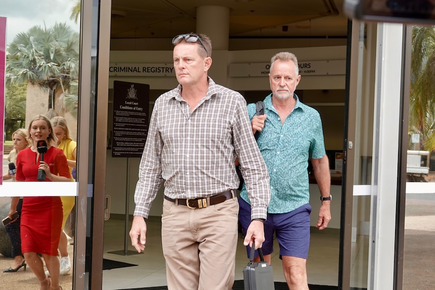 Two men walking out of the doors of the Darwin Local Court.
