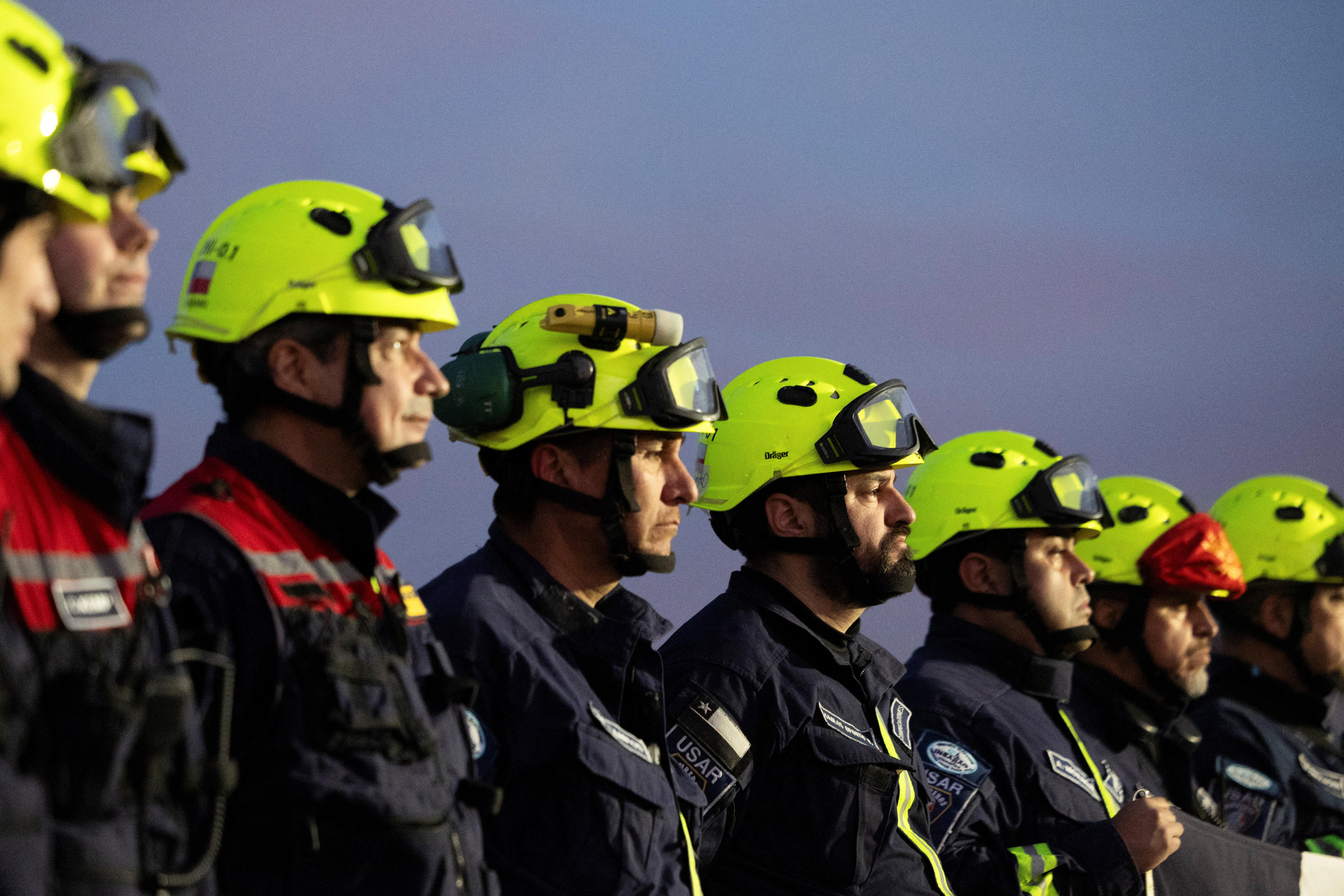 firefighters with neon yellow helmets stand in a line 