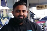 Vishal Plato smiles as he stands on a street in South Yarra on a cloudy day.