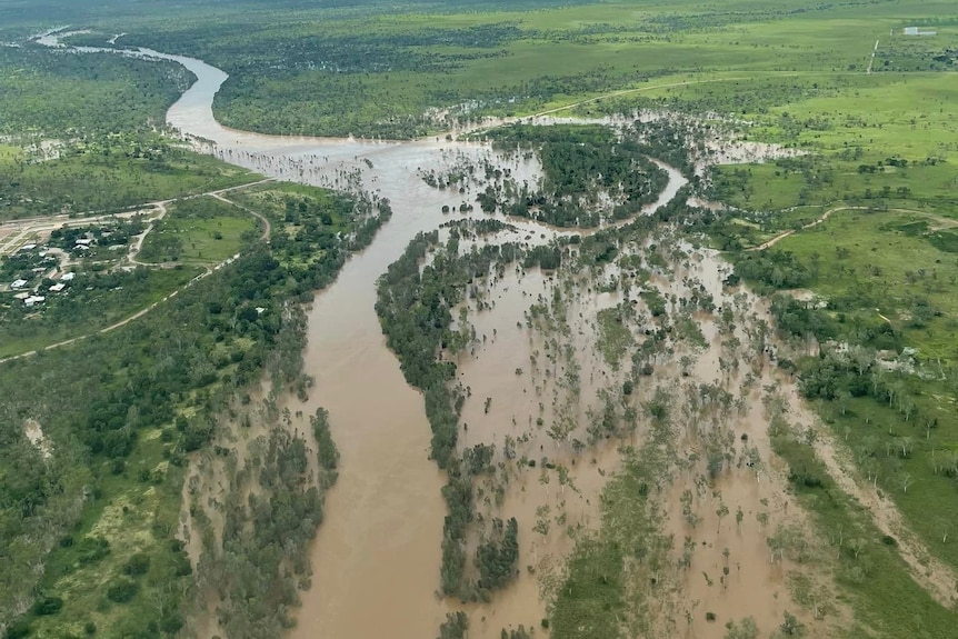an aerial photo of a river in flood next to a small town.