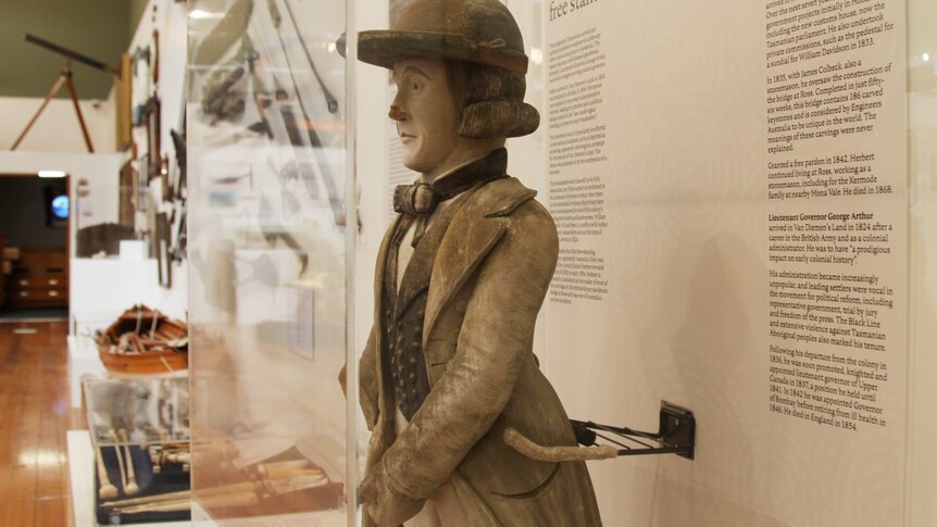 Statue in cabinet of man in colonial dress, holding his penis as he urinates
