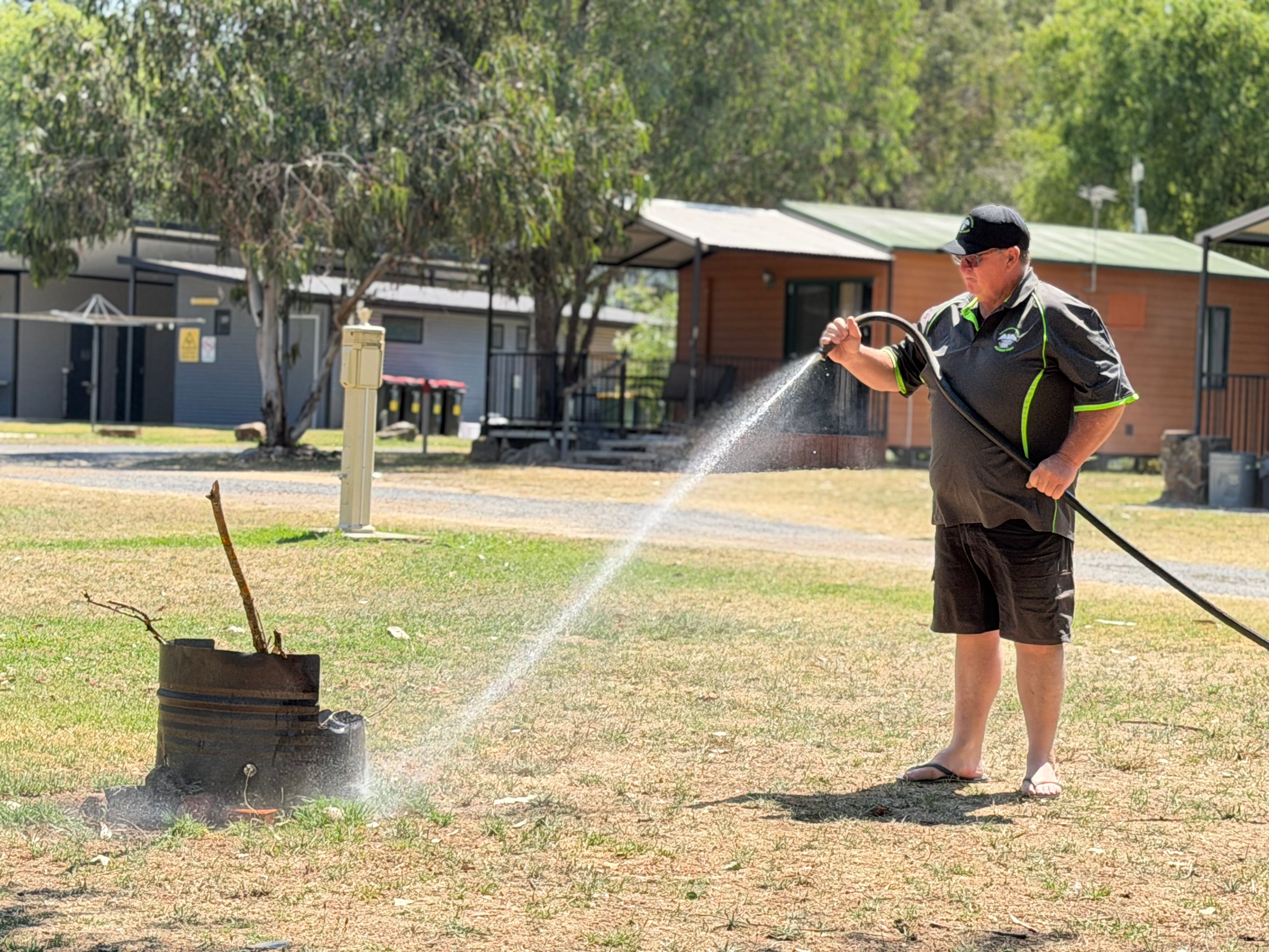 Un hombre usa una manguera sobre el césped.