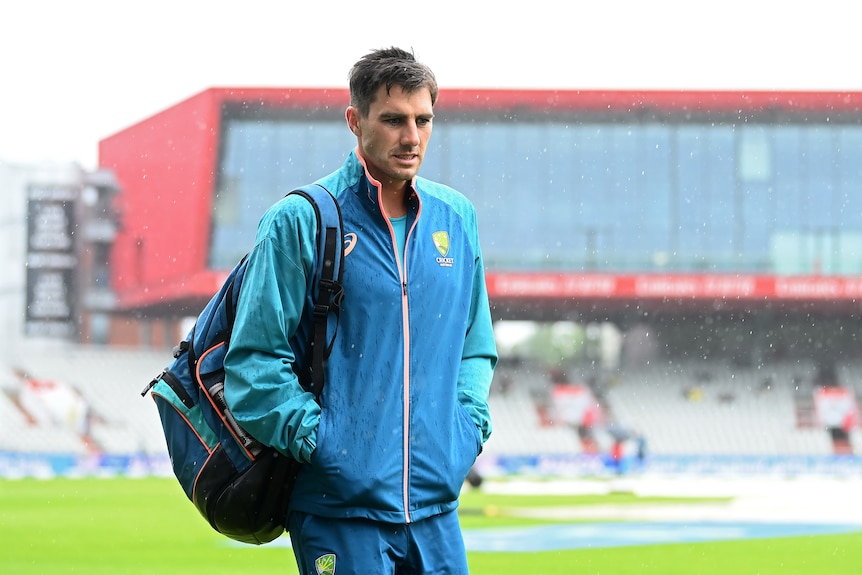 Australia cricket captain Pat Cummins walks through the rain at Old Trafford in his team warm-up gear.