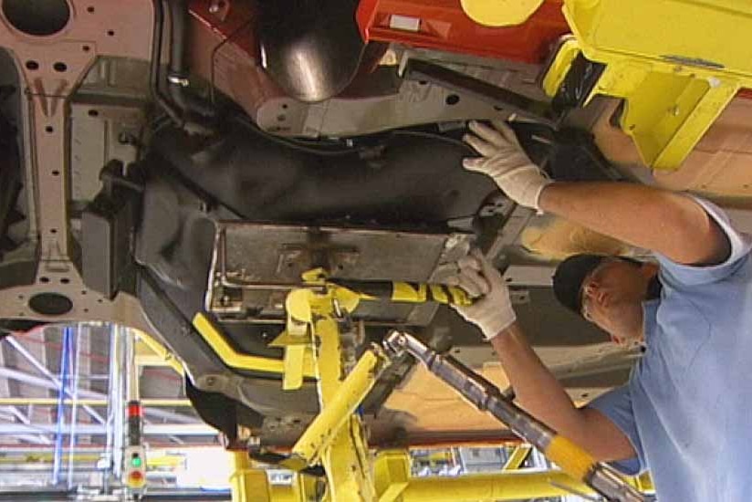 Holden factory worker under car chassis