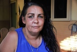 A head and shoulders shot of a woman with long dark hair and a blue top.