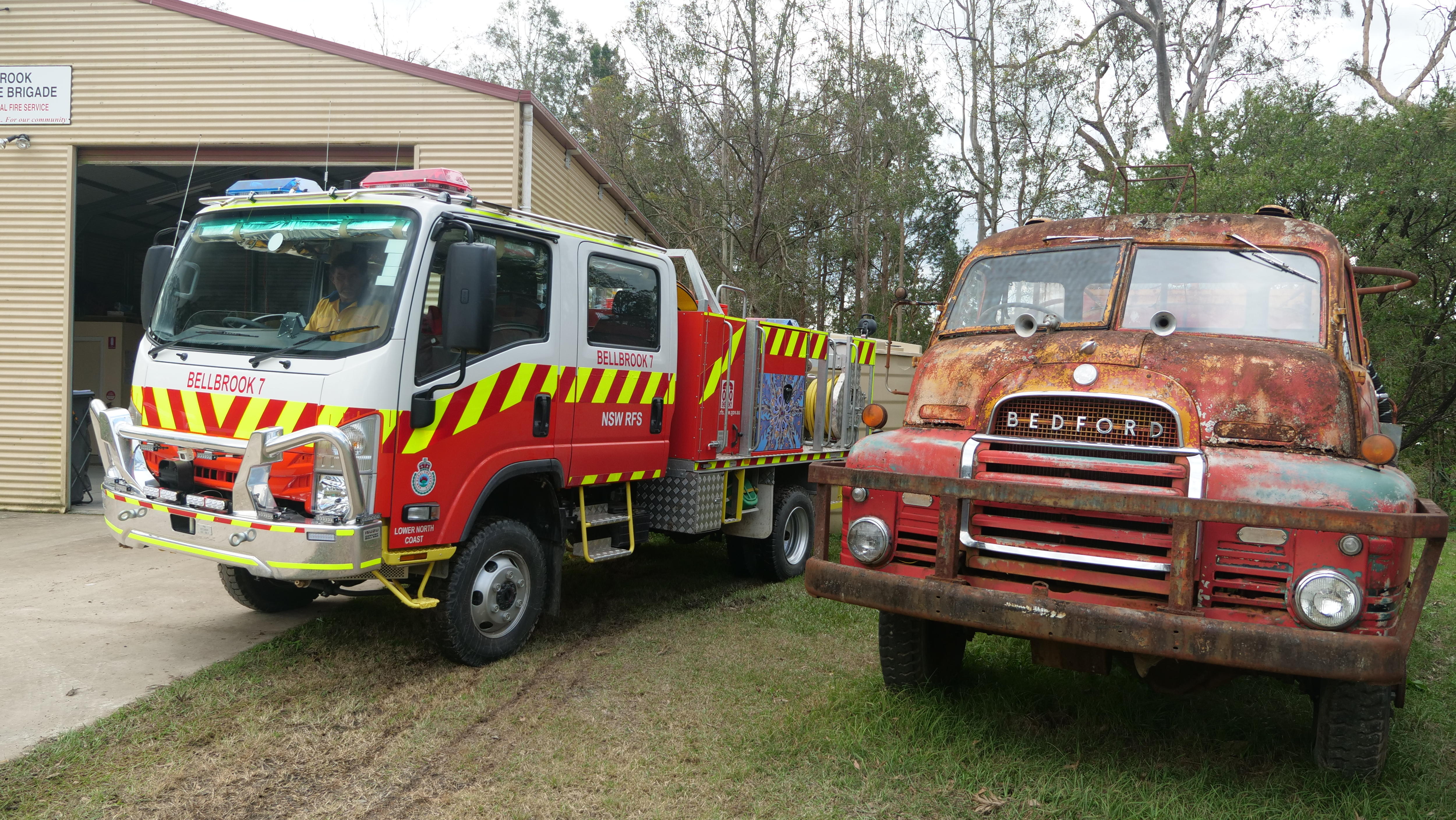 A modern fire truck sitting next to an old rusty fire truck.