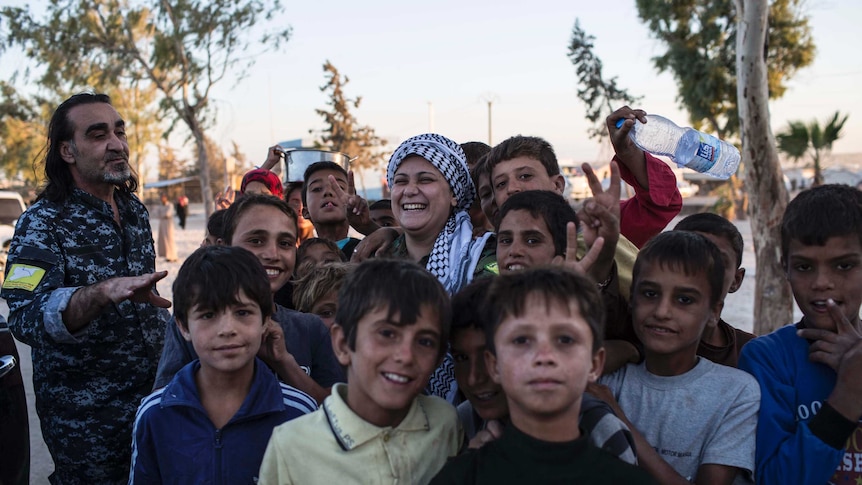 Lilwa surrounded by children at a camp for displaced families