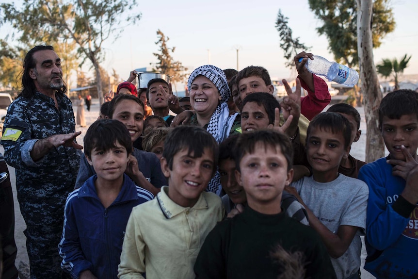 Lilwa surrounded by children at a camp for displaced families