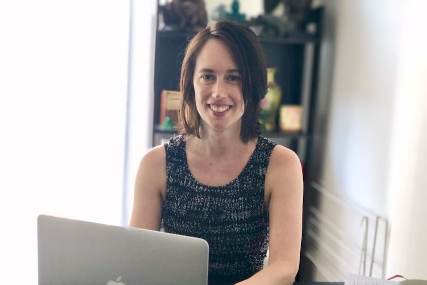 Relationship coach Ruth Sowter sitting at her dining table with lap top smiling