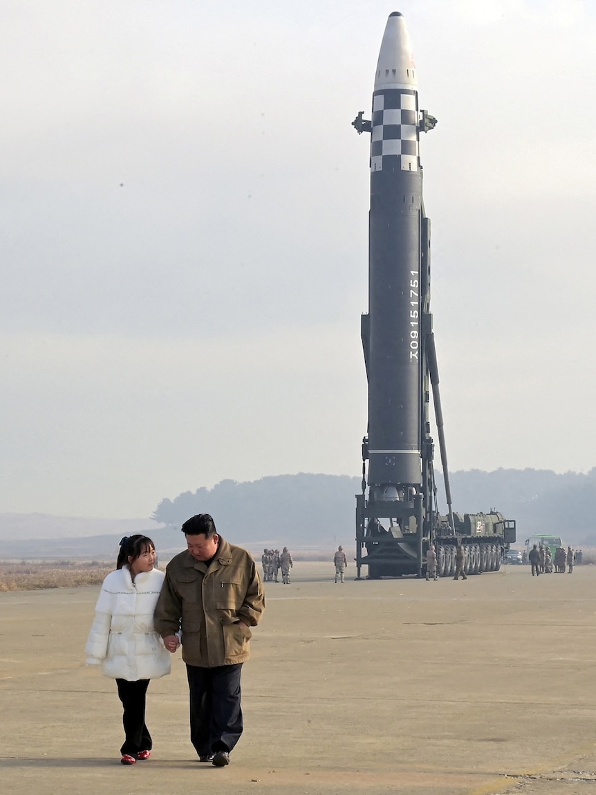 Kim Jong Un walks away from a missile on a tarmac. 