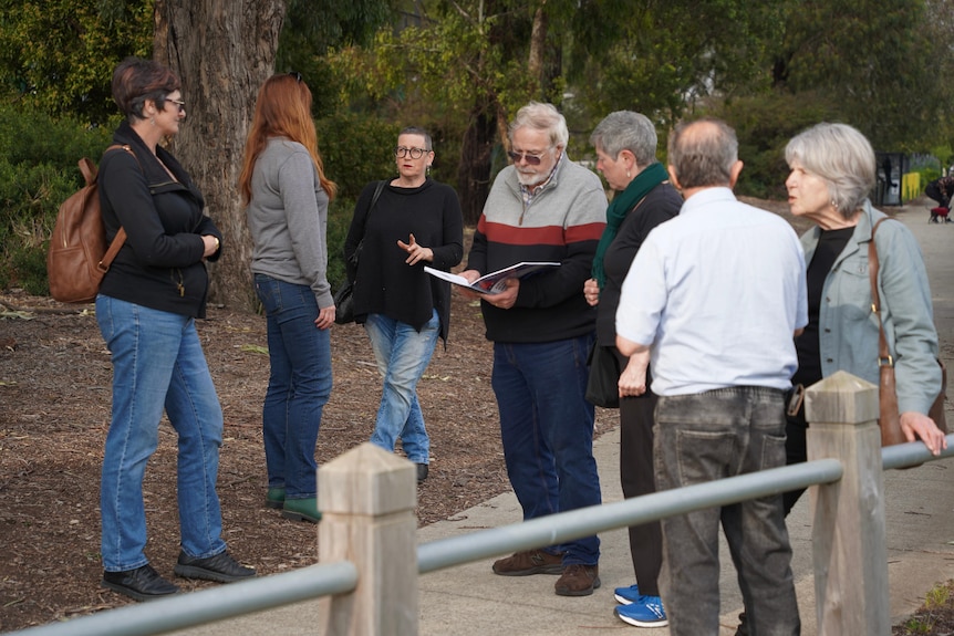A group of people gathered with one man reading a report