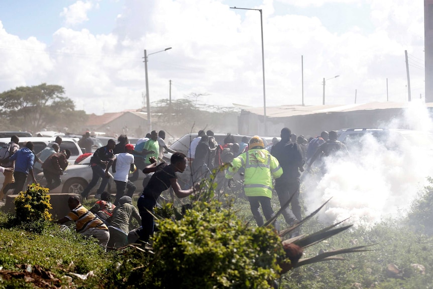 A crowd of people are dispersed by what appears to be tear gas.