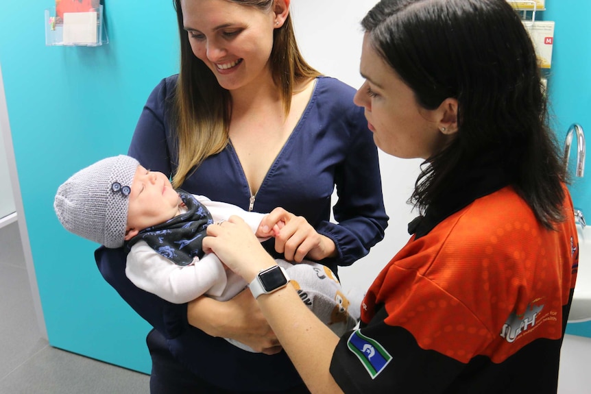 Ms Hauiti cradles her newborn with her midwife nearby.