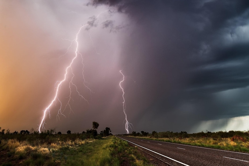 Image of lightning striking the ground during a storm over a remote highway.