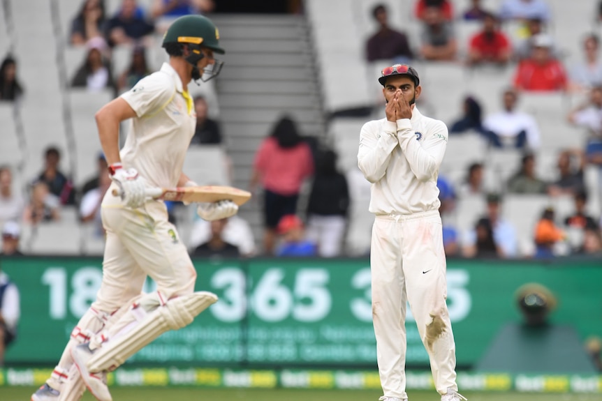 Virat Kohli looks on in frustration as Pat Cummins runs home a single at the MCG