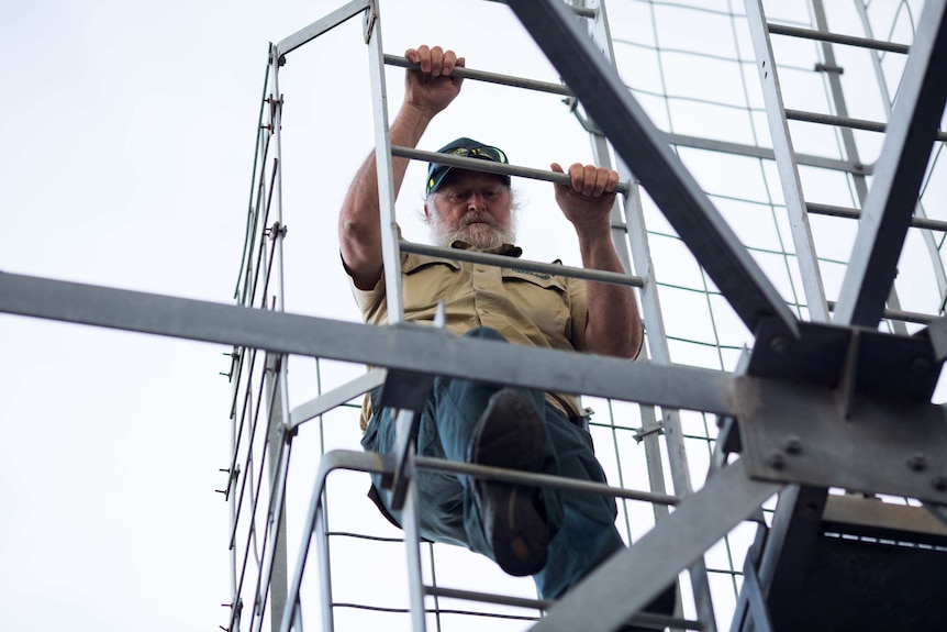 Paul Leishman climbs a steel ladder on his fire tower.