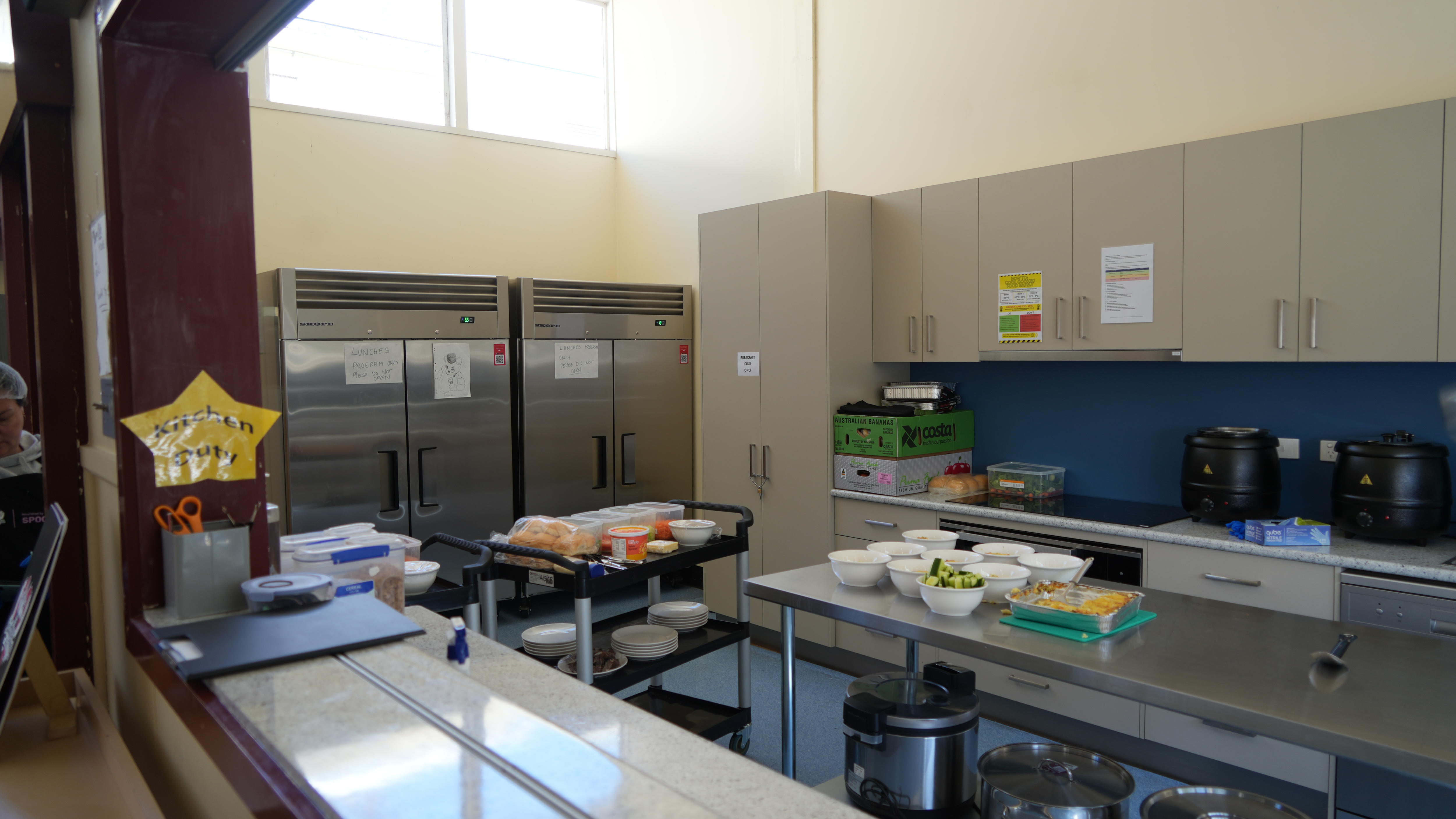 A commercial kitchen housing two fridges, an oven and a prep space.
