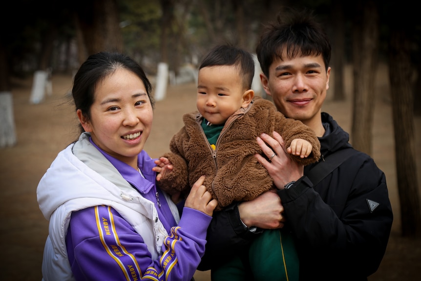 A man and woman hold a small baby 