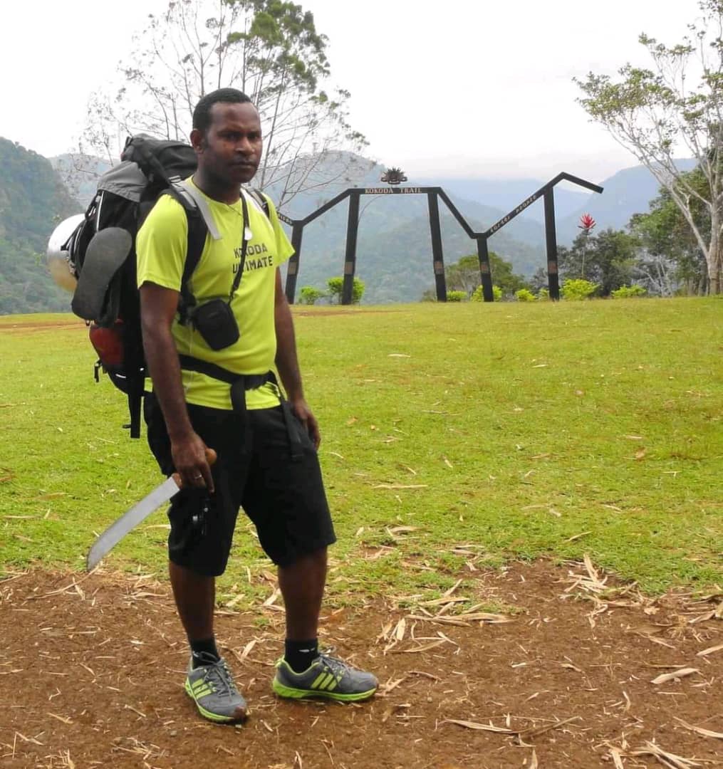 A man wearing a hiking backpack standing at the Kokoda Trail in Papua New Guinea.