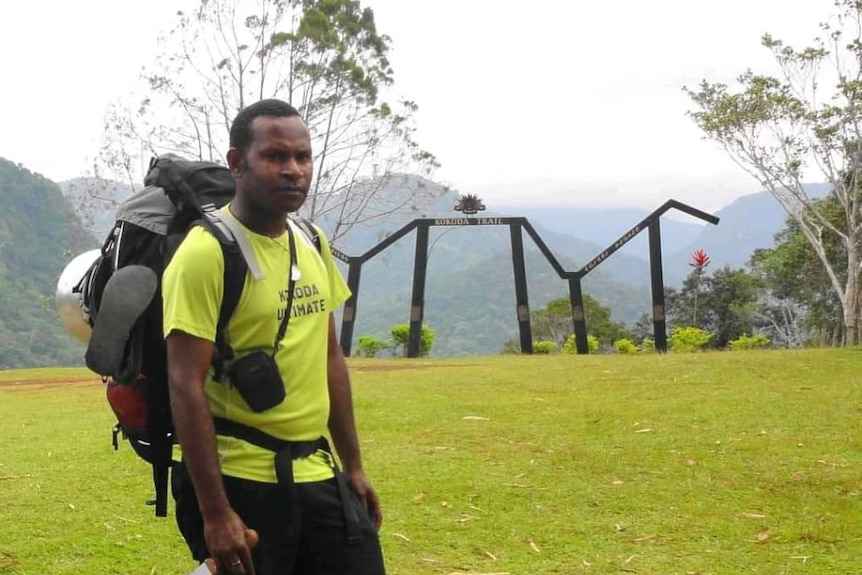 A man wearing a hiking backpack standing at the Kokoda Trail in Papua New Guinea.
