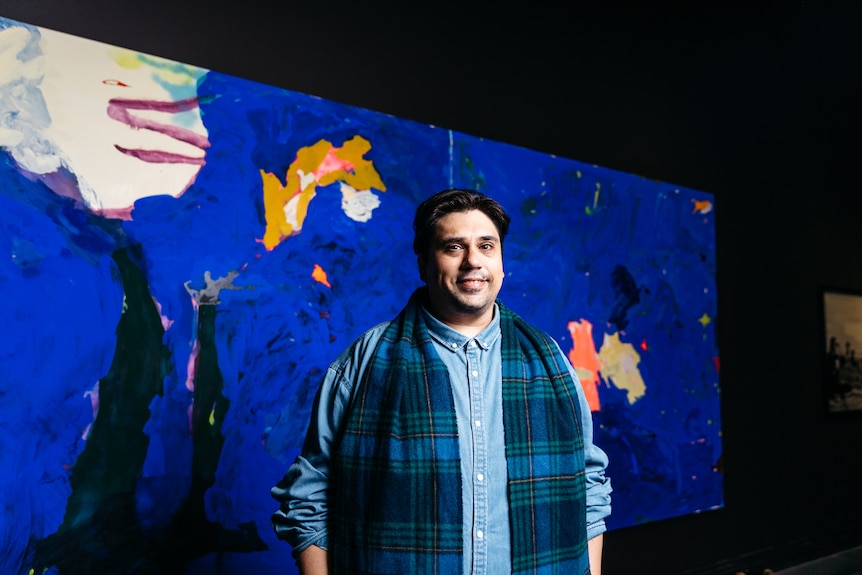 Tom Polo stands in front of his Ramsay Art Prize entry, a bright blue painting on two panels