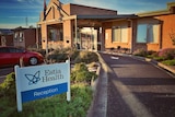 A sign reads 'Estia Health Reception' outside a one-storey brick building.