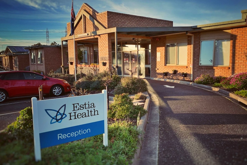 A sign reads 'Estia Health Reception' outside a one-storey brick building.