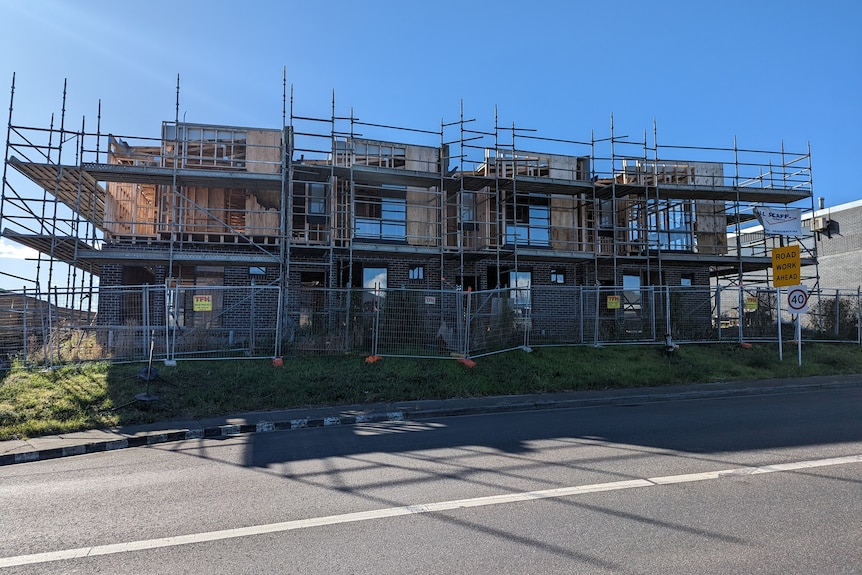 A partly completed building behind a fence