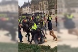 The middle of a screenshot is shown highlighted with two yellow vest protesters kicking a man on the floor.