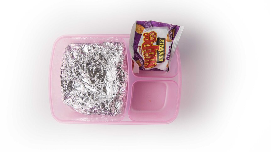 A jam and butter sandwich wrapped in foil and pizza-flavoured Shapes biscuits in a clear purple lunch box.