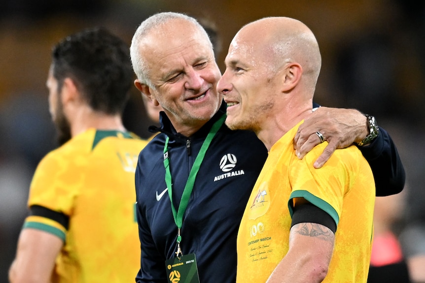Socceroos coach Graham Arnold puts his arm around player Aaron Mooy after a game.