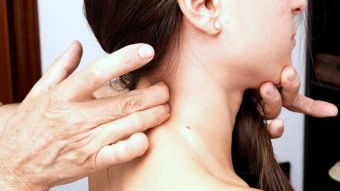 A woman has her neck examined by a doctor.