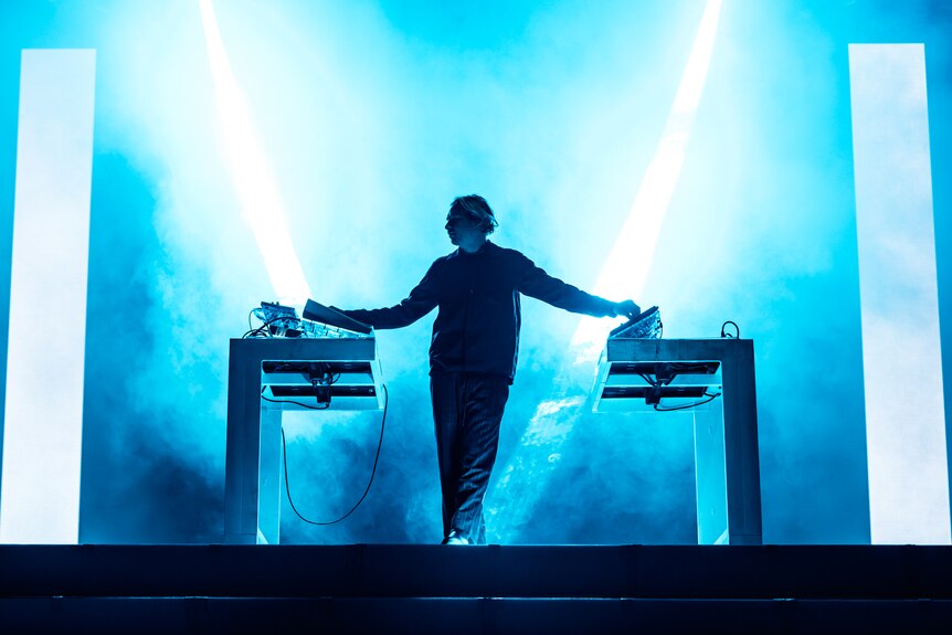 Flume stands between his mixing desk, performing on stage at Spelndour