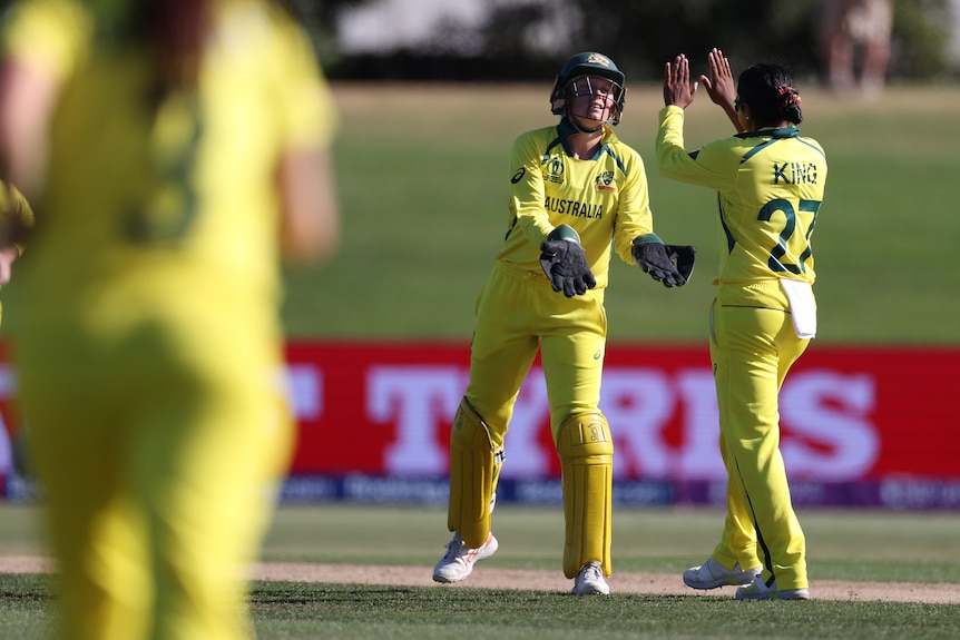 Australia wicketkeeper Alyssa Healy low-fives bowler Alana King during a World Cup game..