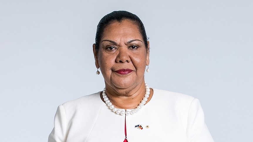 A woman in a white jacket looking at the camera in an official photo.