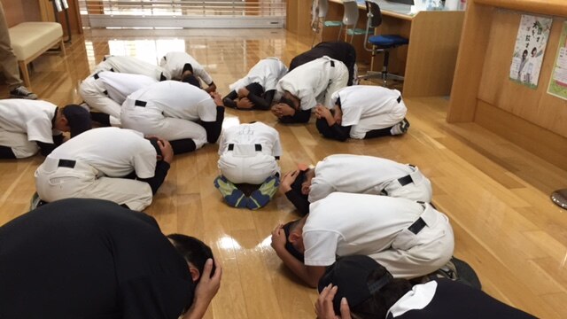 Young boys curled up in a government office with their hands over their heads