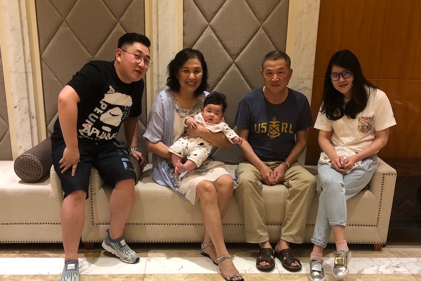 Two women and two men pose for a photo with a baby
