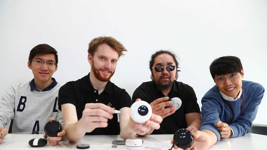 Four men sitting in a row holding technology.