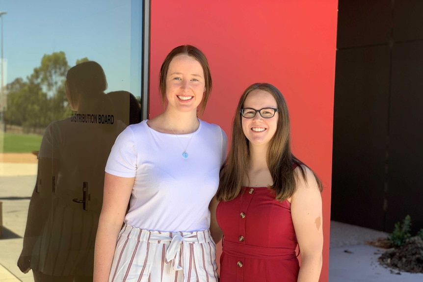 two young women smile at the camera