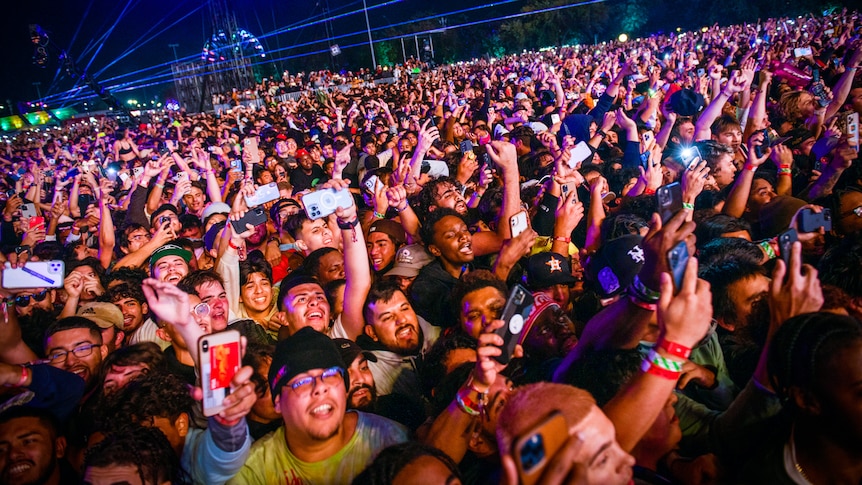 A huge crowd of people holding up their phones at a night time gig