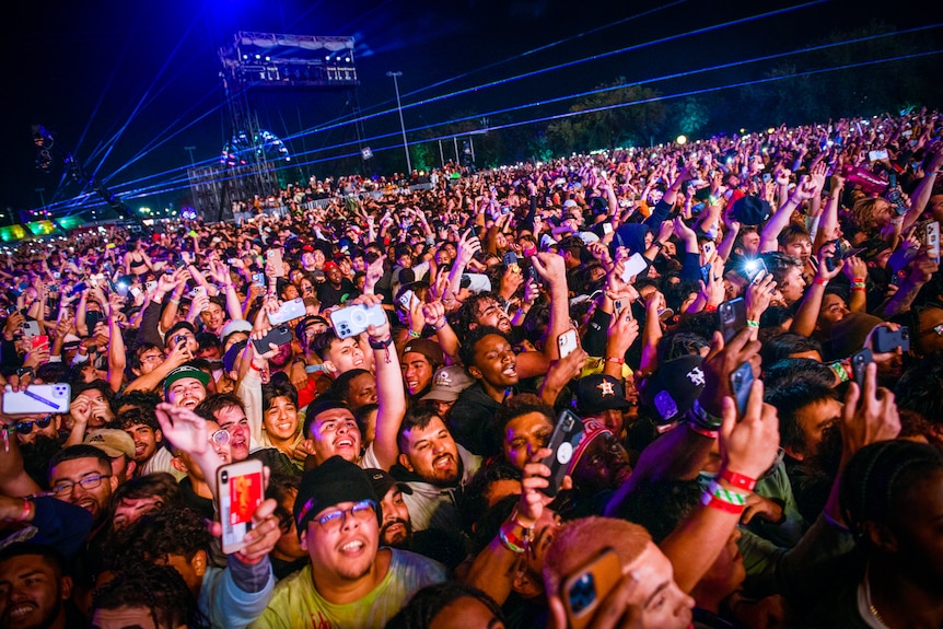 A huge crowd of people holding up their phones at a night time gig