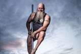 Man approaching 60, sporting bushy grey beard, balances on pole