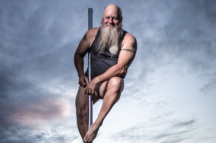 Man approaching 60, sporting bushy grey beard, balances on pole