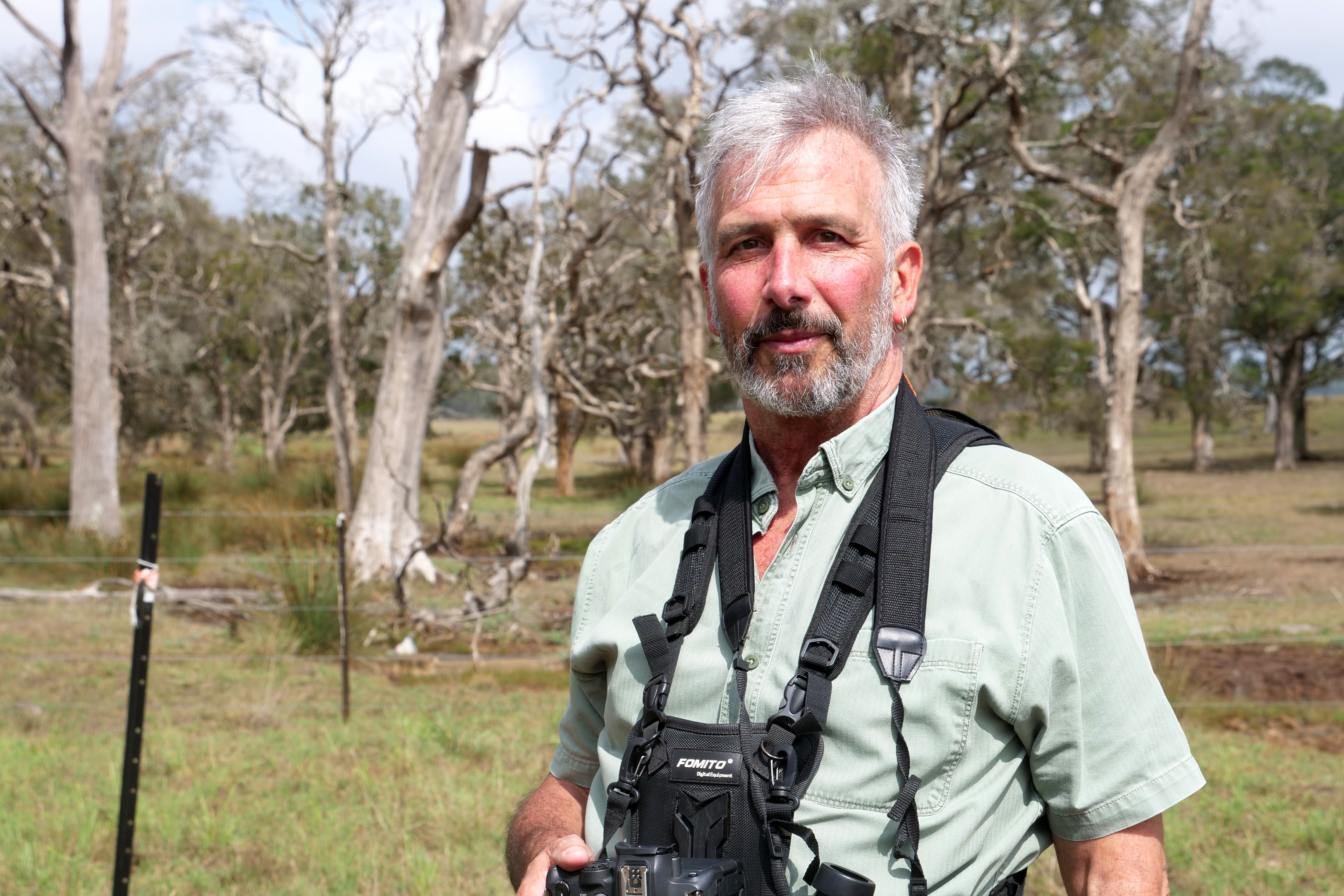 um homem com uma câmera pendurada no pescoço olha para frente